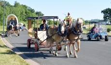 People in a more modern contrivance pass the Friendship Wagon Train as it heads south on North 10th Street on its way out of town.